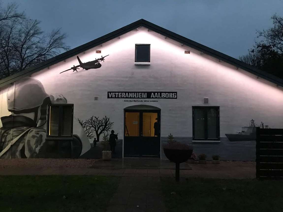 Gavlen på Veteranhjem Aalborg i mørke, hvor maleri af soldat og fly er belyst
