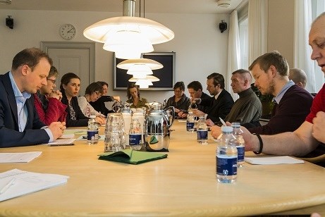 Mødedeltagere sidder ved et bord og taler henover bordet